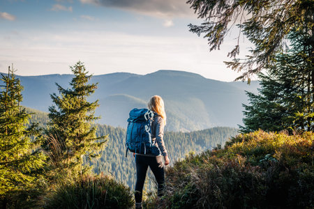 Woman with backpack hiking in mountain forest at natural parkland Jeseniky, Czech Republic. Traveler...