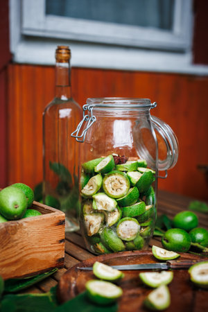 Making homemade walnut liqueur. Unripe nuts in jar and alcohol in bottle on tableの写真素材
