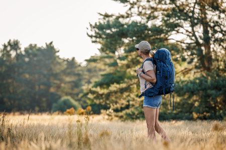 Woman with backpack hiking in forest. Trekking in wilderness alone. Summer adventure in natureの写真素材