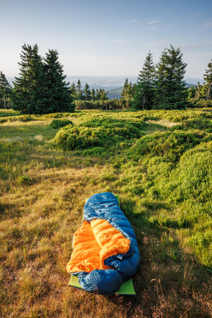Open sleeping bag on mat at mountains. Bivouac and camping outdoors under clear skyの写真素材