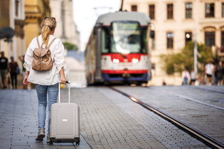 Woman traveler with suitcase and backpack walking on street. Travel and vacation in European city Olomouc, Czech Republicの写真素材