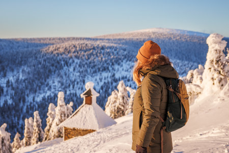 Woman hiking in Jeseniky mountains in winter. Female tourist looking at beautiful snow landscape from summit known as Red Mountainの写真素材