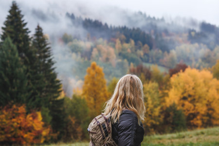 Hiking in autumn forest. Woman during hike in mountain. Fog weatherの写真素材