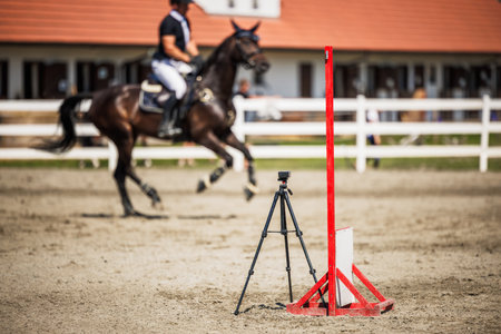 Timer or digital stopwatch at the finish line. Horse equestrian show jumping competition. Defocused horse with unrecognizable jockeyの写真素材