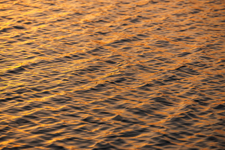 Reflection of golden sunset on water surface. Full frame natural backgrounds of lake or sea wavesの写真素材