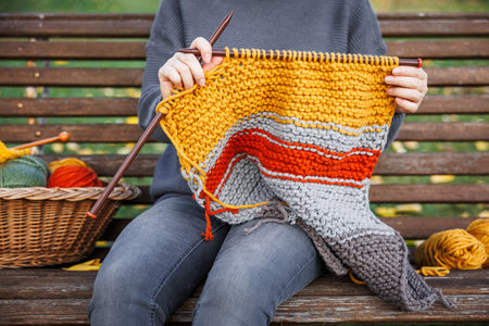 Woman sitting on bench and knitting woolen sweater. Leisure activities and hobbiesの写真素材