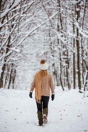 Woman wearing sweater, knit hat and scarf in snow forest. Walk in winter nature.の写真素材