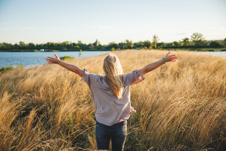 Wonder and joy of that moment outdoors. Happy woman feels fresh air and wind in her hair. Mindfulness and enjoyment of summer sunny day at lakeの写真素材