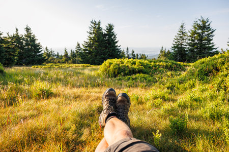 Crossed male legs with leather hiking boots. Relaxation in mountain forest during trekkingの写真素材