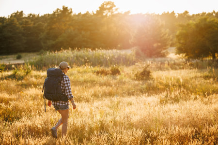 Solo hiker on journey. Summer hiking and adventure. Woman with backpack is trekking in nature on long trip aloneの写真素材