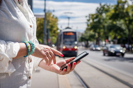 Public transportation in Vienna. Woman tourist buying online travel or transport ticket to tramway with mobile app on her smart phoneの写真素材