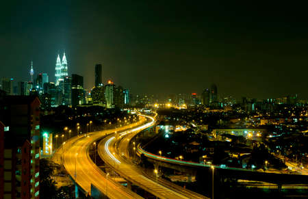 Light trail at busy highway with the view of kuala lumpur city