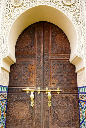 Moroccan style door latch on an intricately carved wooden doorの写真素材