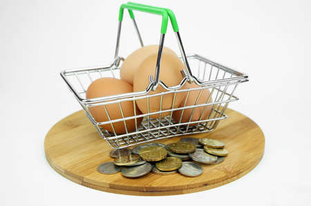 Eggs in small container and shopping cart with coins. financial conceptの写真素材