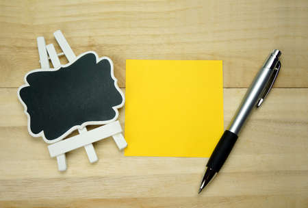 Blackboard, paper and pen on wooden table