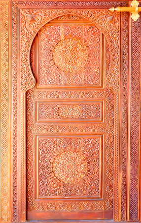 Moroccan style door latch on an intricately carved wooden door                                の写真素材