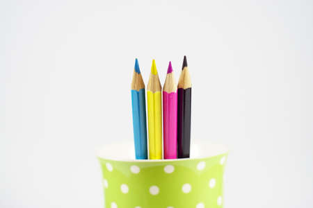 Multicolor pencils in green polka dot pen holder isolated on whiteの写真素材