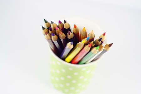 Multicolor pencils in green polka dot pen holder isolated on whiteの写真素材