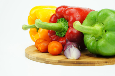 Close up image of colorful peppers with cherry tomatoes and onion over white backgroundの写真素材