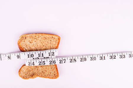slice of bread with measurement tape on white backgroundの写真素材