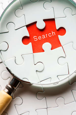 Magnifying glass searching missing puzzle peace "SEARCH"の写真素材