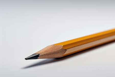 A single, perfectly sharpened pencil sits on a minimalist white background, illustrating the simplicity of creativity. The image highlights the potential for ideas and artistry in a single writing instrument.の素材