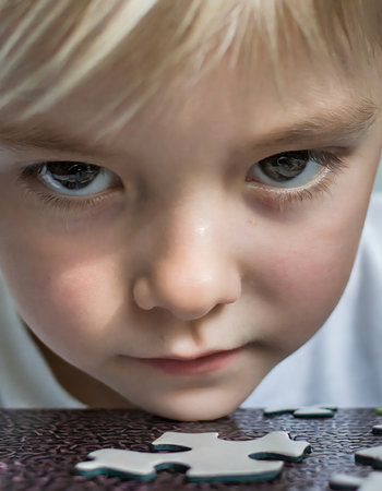 Capture the wonder of a young child as they focus on solving a puzzle, their bright eyes filled with curiosity and determination. This close-up image highlights the essence of childhood exploration and learning.の素材
