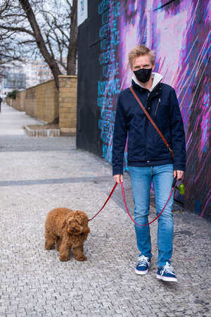 Man walks dog wearing face mask protectionの写真素材