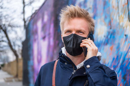 European man using phone wearing face mask protectionの写真素材