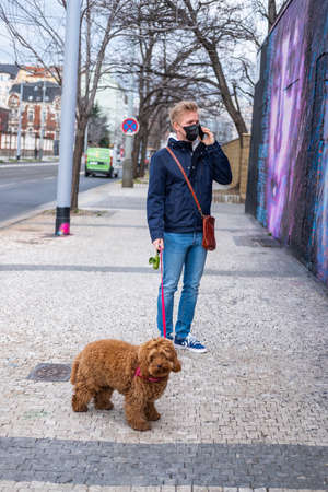 Man walks dog wearing face mask protectionの写真素材