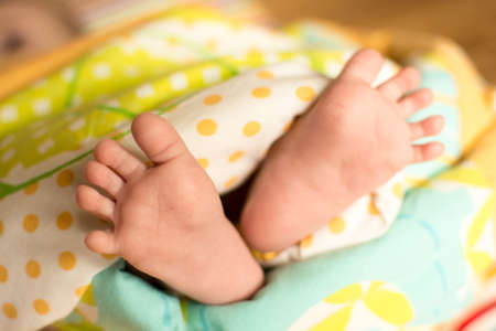 cute little baby foot on textured yellow quilt coverの写真素材