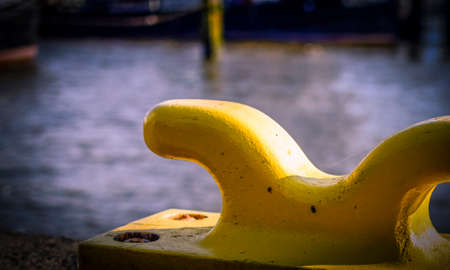 Horizontal oriented picture of port pier with yellow mooring bollard.の写真素材