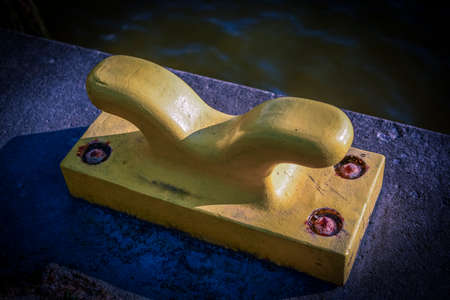 Horizontal oriented picture of port pier with yellow mooring bollard.の写真素材