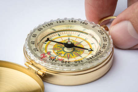 A High Quality Brass Compass in one mans hand clipping path present on maximum resolution downloads with blurry white backgroundの写真素材