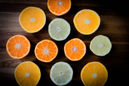 Citrus fruit cut in half - oranges, lemons, tangerines on a wooden backgroundの写真素材