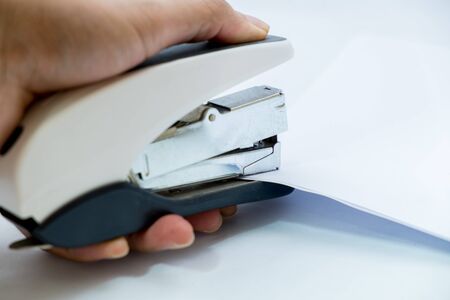binding papers with stapler by hands and white backgroundの写真素材