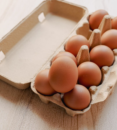 Eggs in a carton box on a white wooden backgroundの写真素材