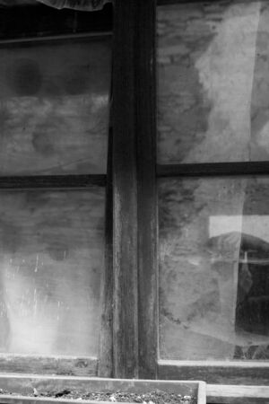 A wooden window of an old house with spider web and worn glassの写真素材