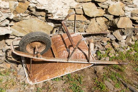 a rusty wheelbarrow overturned and abandoned in a farmの写真素材