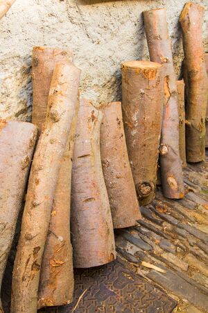 cut wooden logs leaning against the wall of an old country houseの写真素材