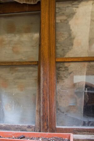 A wooden window of an old house with spider web and worn glassの写真素材