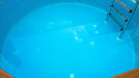 blue backdrop of a small swimming pool with ladderの写真素材