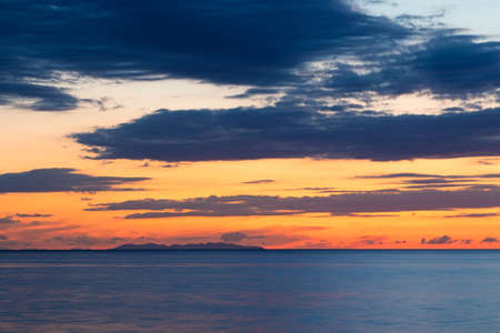 Sunset behind Capraia island on Mediterranean sea in summer time, Italyの写真素材