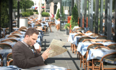 Resting businessman drinking coffee and reading newspaper in the restaurant - outsideの写真素材