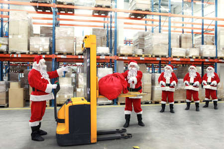 group of santa clauses standing in the line for the sacks of gifts in storehouseの写真素材