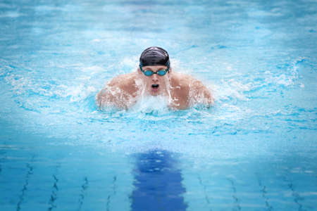 Swimmer in cap breathing performing the butterfly stroke の写真素材