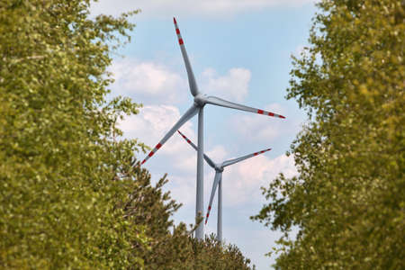 Wind energy turbines surrounded by blurred summer trees