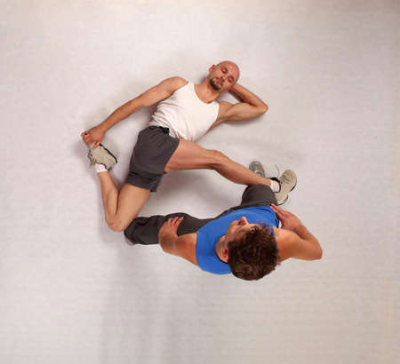 muscular man stretching  with personal trainer in studio