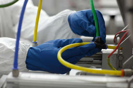 hands in blue gloves fixing problem at industrial process line - close up の写真素材