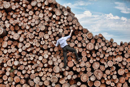 	Challenge- businessman climbing the large pile of logsの写真素材